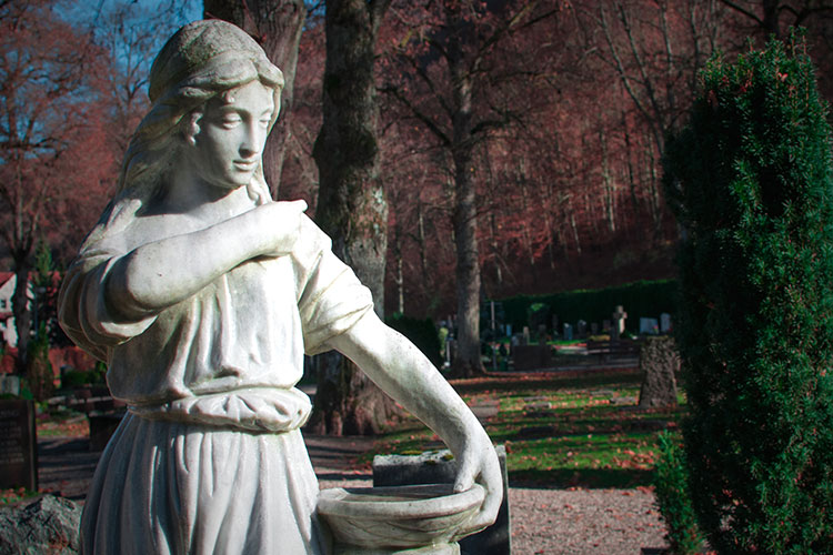 Steinskulptur einer trauernden Figur auf einem Friedhof in Bad Urach